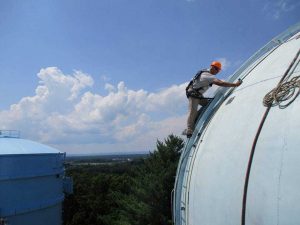 worker climbing on side of water tower